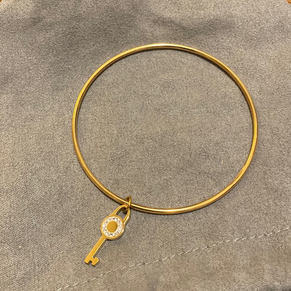Gold tone bangle bracelet with hanging key charm with stones